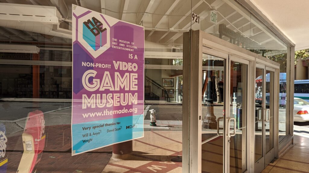 Entrance to the Museum of Art and Digital Entertainment. A poster reads 'The Museum of Art and Digital Entertainment is a non-profit video game museum. www.themade.org'